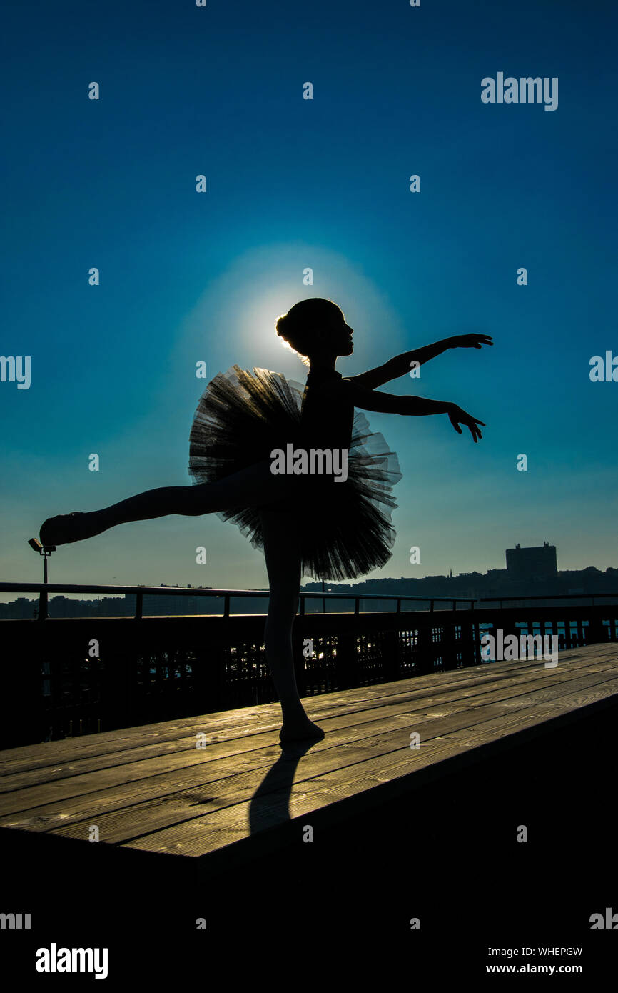 Silhouette Ballerina ballando sul tavolo di legno al Molo contro Sky  durante la giornata di sole Foto stock - Alamy