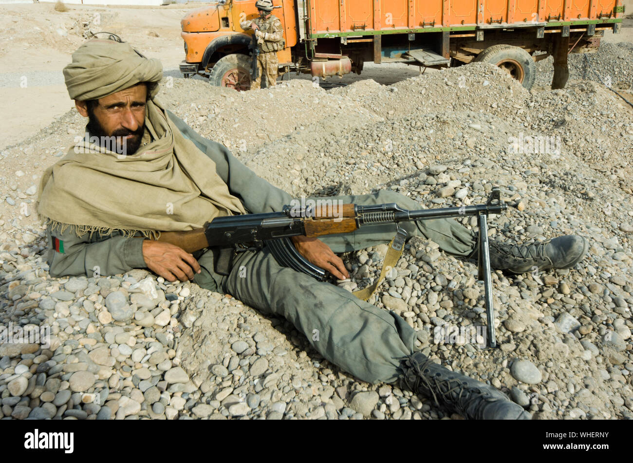 Un membro dell'esercito nazionale afghano (ANA) prendendo una posa rilassata durante le operazioni di sicurezza nella provincia di Helmand, Afghanistan meridionale Foto Stock