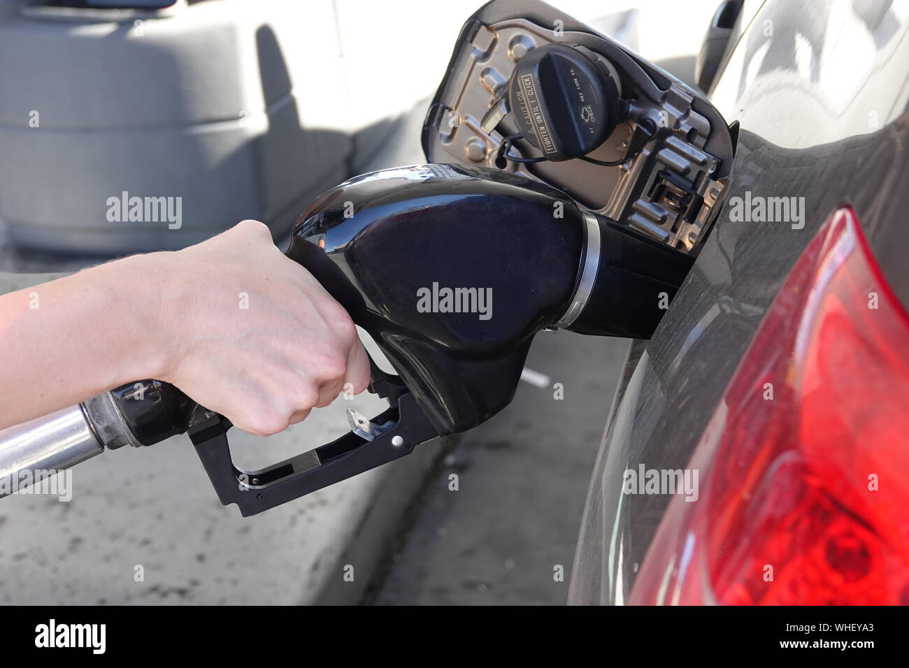 Una mano è illustrato il funzionamento di un gas ugello della pompa in corrispondenza di una stazione di riempimento in una vista ravvicinata. Foto Stock