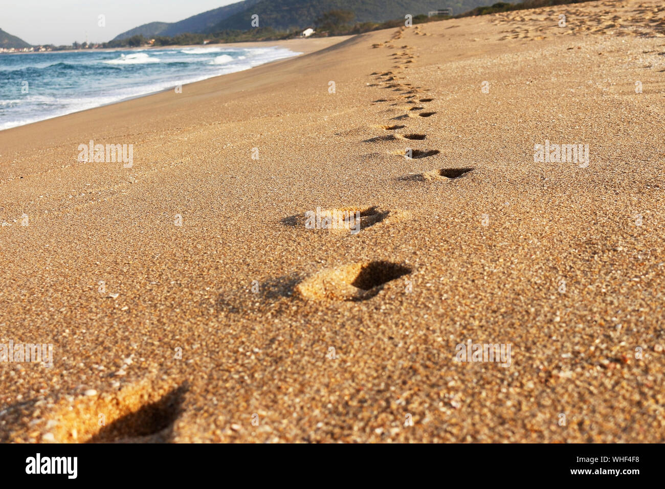 impronte sulla spiaggia di sabbia. Una spiaggia deserta al crepuscolo. Foto Stock