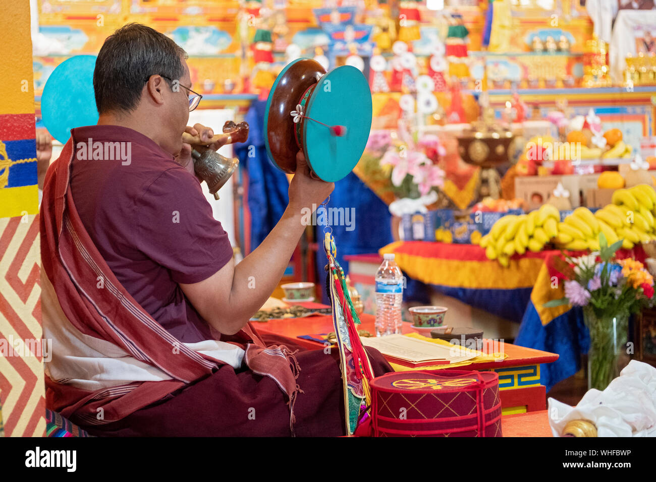 Un monaco buddista conduce una puja servizio in un tempio mentre il terminale voce squilla una campana e la rotazione di un tamburo damaru. In Elmhurst, Queens, a New York City. Foto Stock