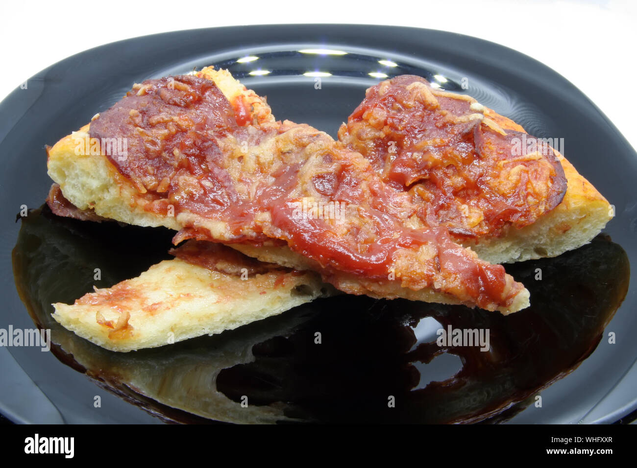 Pizza tagli su una piastra nera. Trancio di pizza su una piastra nera. Foto Stock