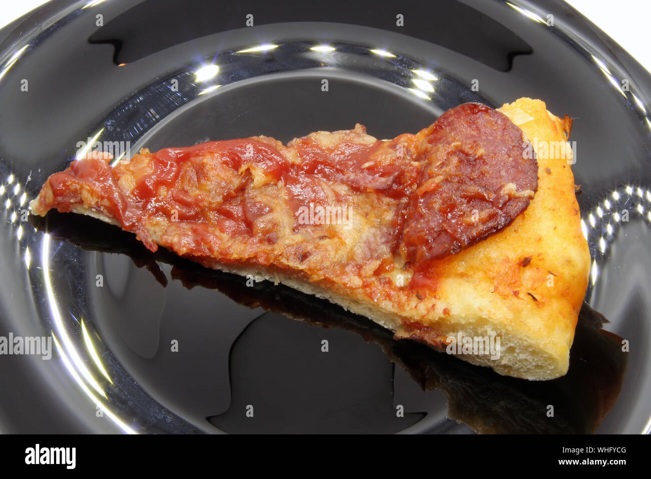 Pizza tagli su una piastra nera. Trancio di pizza su una piastra nera. Foto Stock