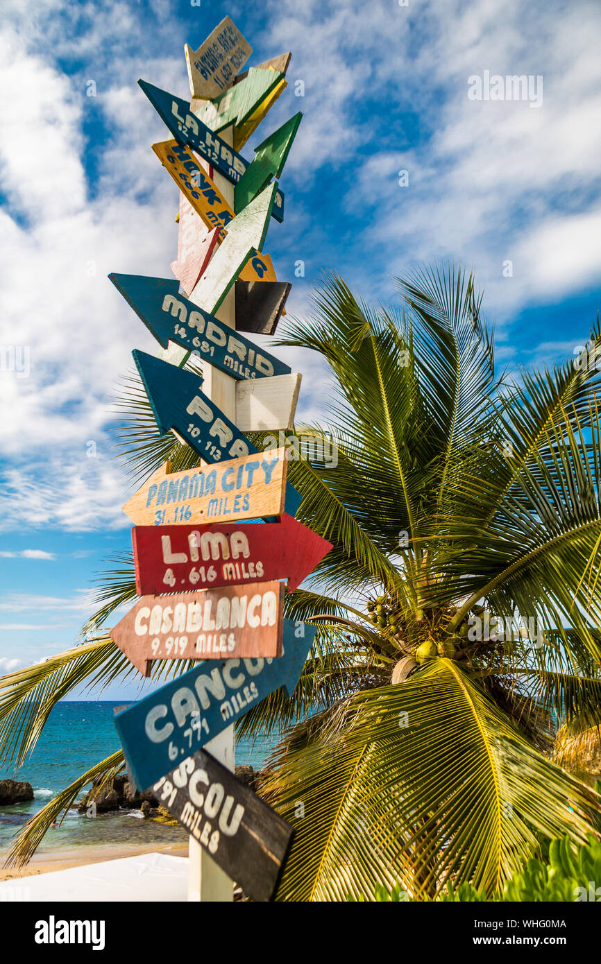 Segno direzionale sulla spiaggia che indica diverse destinazioni wold, fotografato in Repubblica Dominicana. Foto Stock