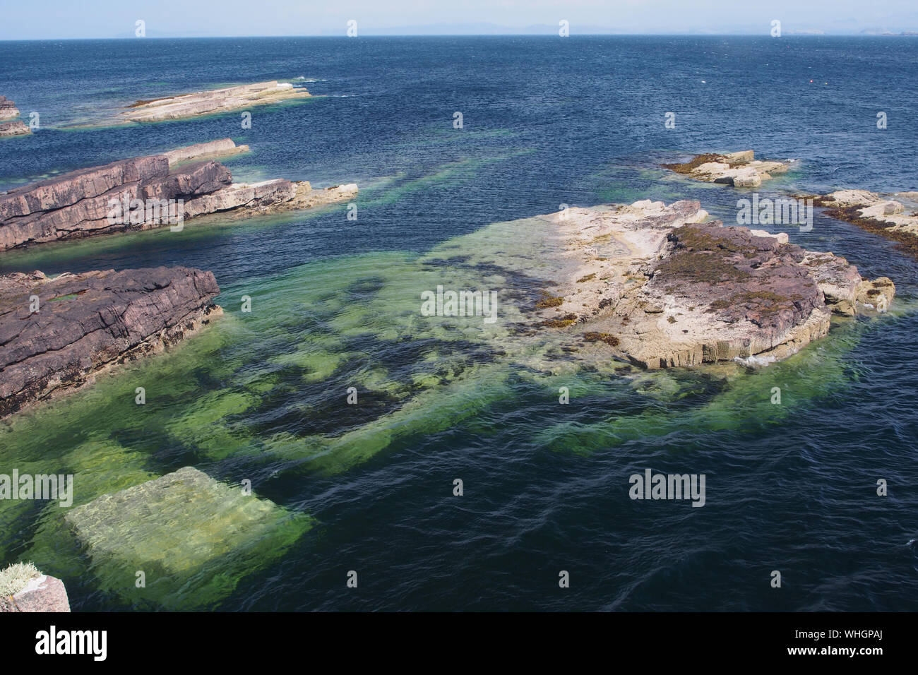 Una vista guardando al mare con metà rocce sommerse, profondo mare blu, i trend con orizzonte di riferimento e i colori naturali sulla penisola Stoer, Sutherland, Scozia Foto Stock