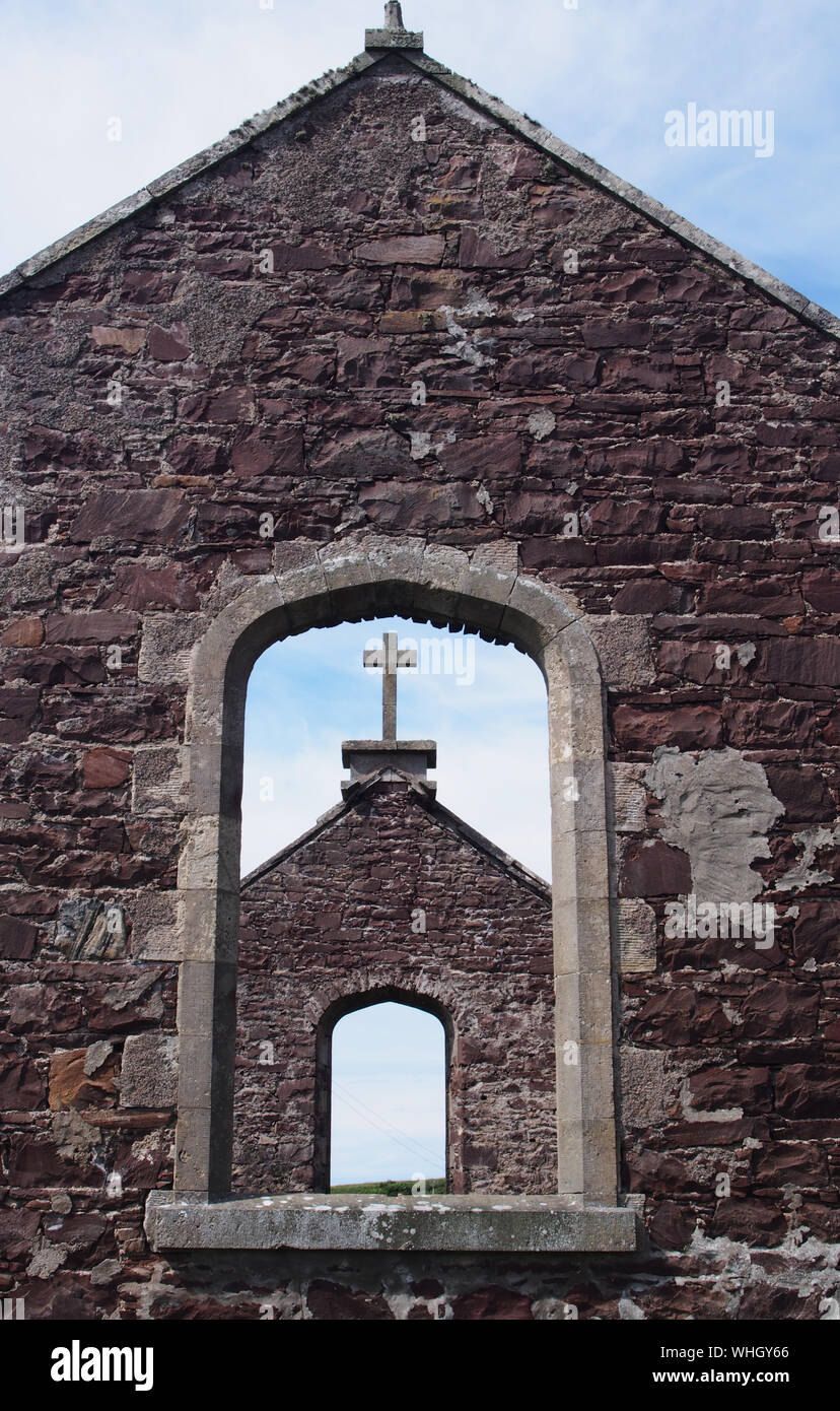 Una vista di una chiesa abbandonata di guardare attraverso una finestra sul frontone per altri gable end con una croce sulla parte superiore e Finestra opposta nel nord della Scozia Foto Stock