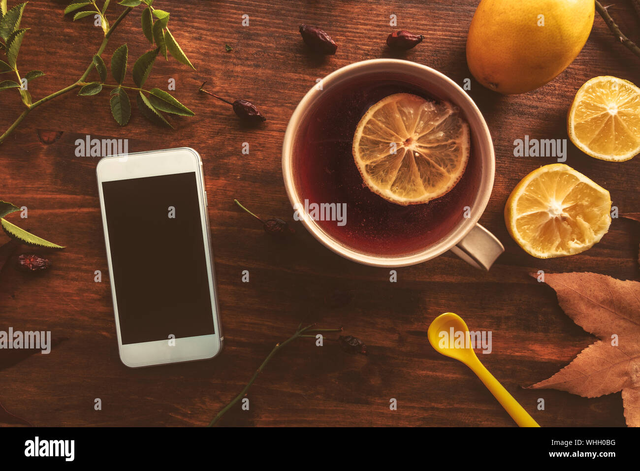 Rosa Mosqueta tè in radica con schermo vuoto smartphone e limone, vista dall'alto del bicchiere sul tavolo Foto Stock