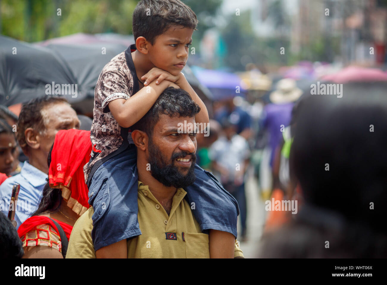 Kochi, Kerala, India - 2 Settembre 2019 - Kid guardando la processione seduto sulla sua spalla padri durante la processione Athachamayam Foto Stock