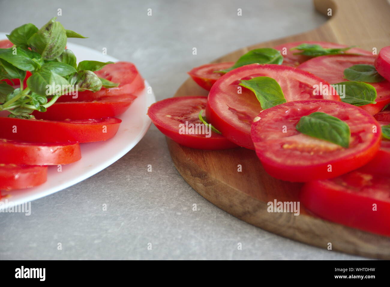 Closeup colpo di fette di pomodoro con basilico su una piastra e il bordo di taglio Foto Stock