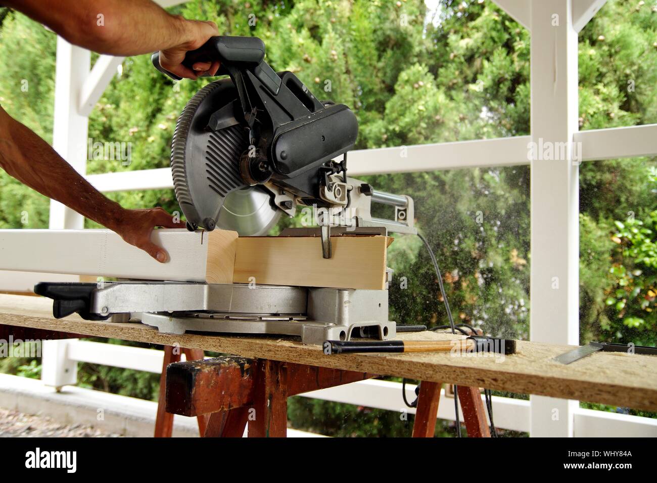 Carpenter utilizzando una sega circolare per il taglio di una trave di  legno. Macchine per la lavorazione del legno e la produzione di  falegnameria. Travi in legno di abete rosso, costruzione esterna.