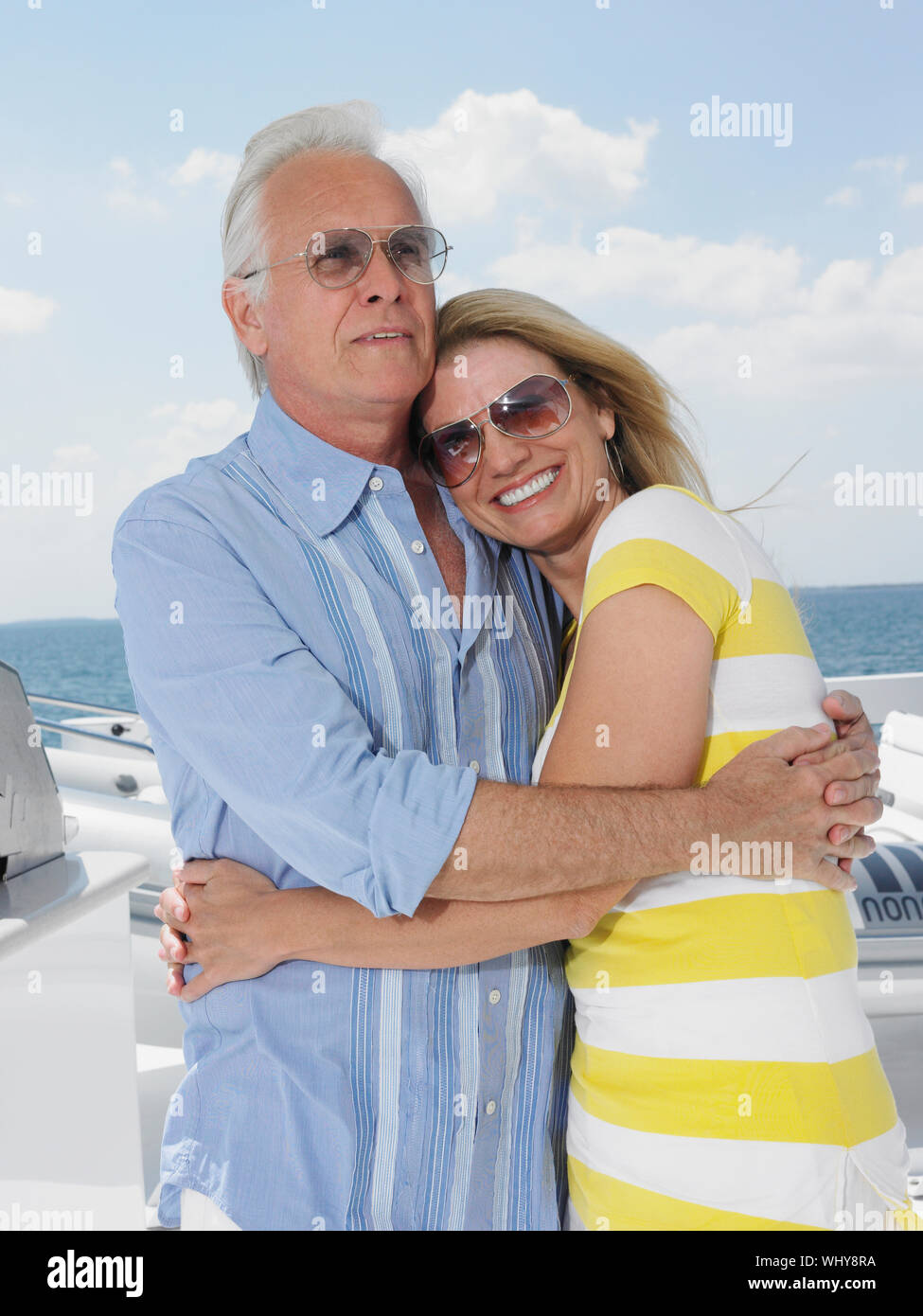 Felice Coppia di mezza età con occhiali da sole mentre abbracciando su yacht Foto Stock