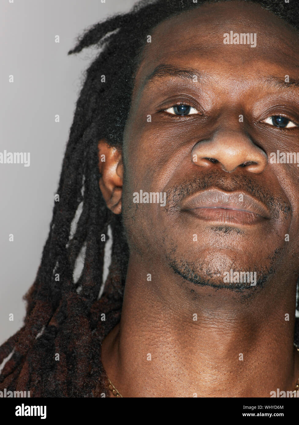 Primo piano della African American uomo con dreadlocks su sfondo grigio Foto Stock