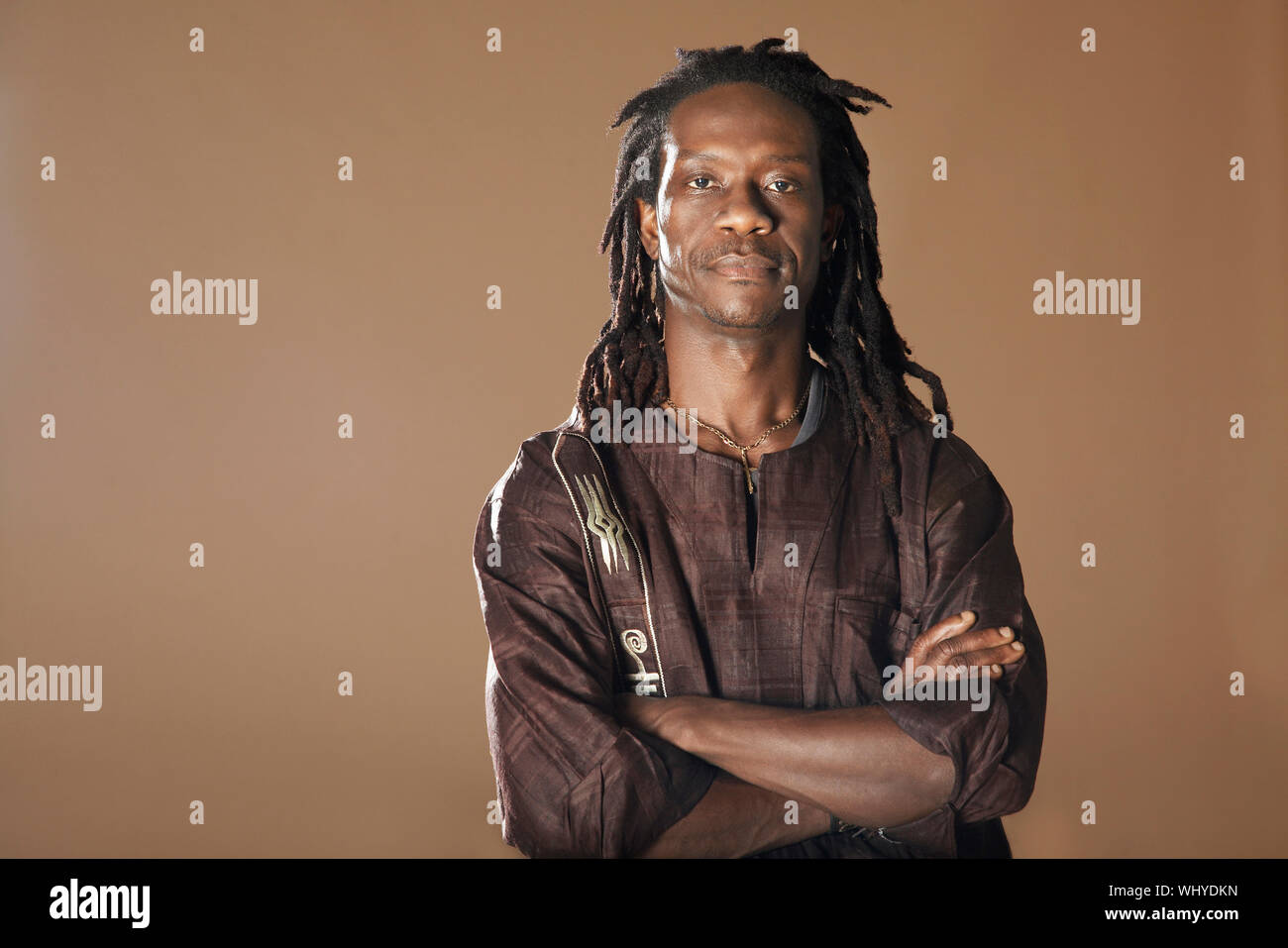 Ritratto di fiducioso African American uomo con le braccia incrociate isolato su sfondo marrone Foto Stock