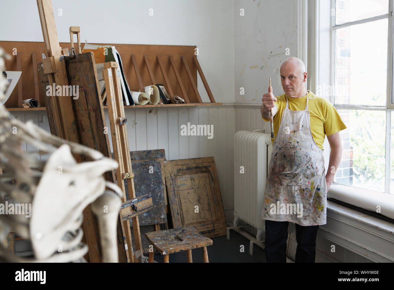 Di mezza età artista maschio studiando scheletro in studio Foto Stock