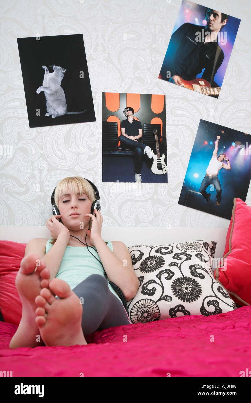 Bella ragazza adolescente ascoltare musica su cuffie a letto Foto Stock