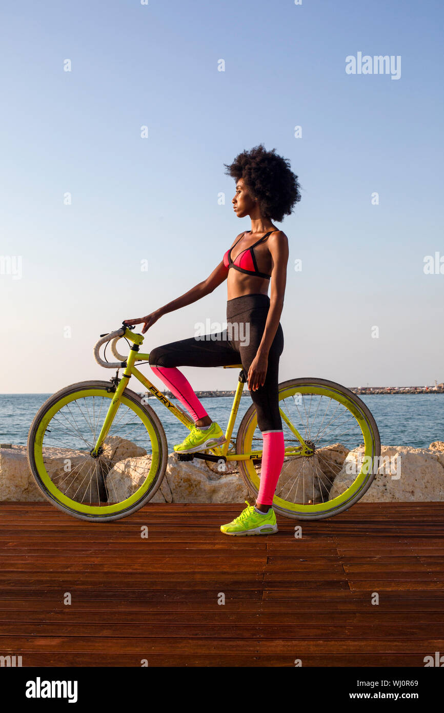 Atletica Giovane donna in abbigliamento sportivo con la sua bicicletta da strada vicino al mare Foto Stock