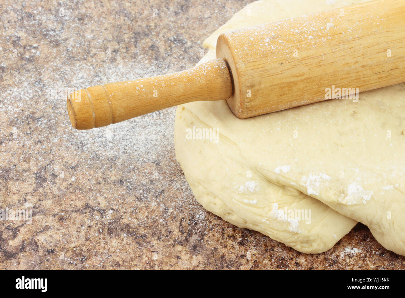 Close up di pasta di pane essendo arrotolato su una pietra sul bancone. Foto Stock