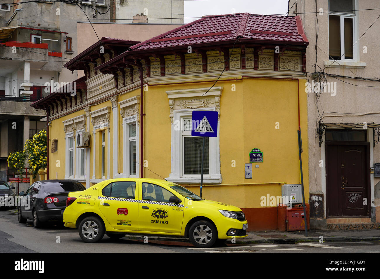 Giallo taxi di fronte ad un edificio fatiscente deterioramento, Bucarest Romania Foto Stock