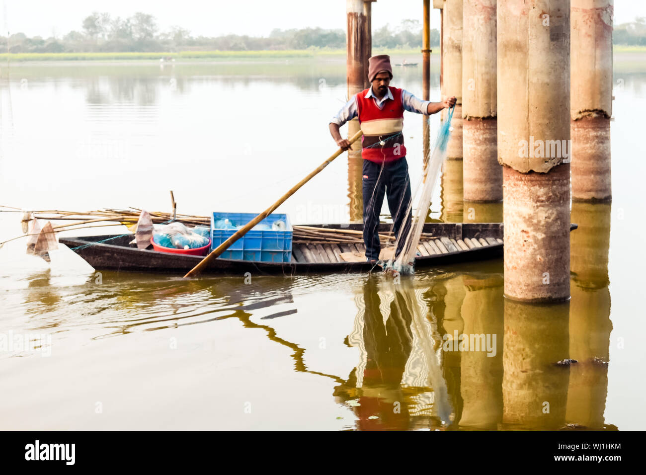 Il Kerala, India, 10 Gennaio 2018 - un pescatore locale pesca con la sua rete da pesca su una barca a remi a Kerala backwaters area al Tramonto Tramonto. Foto Stock