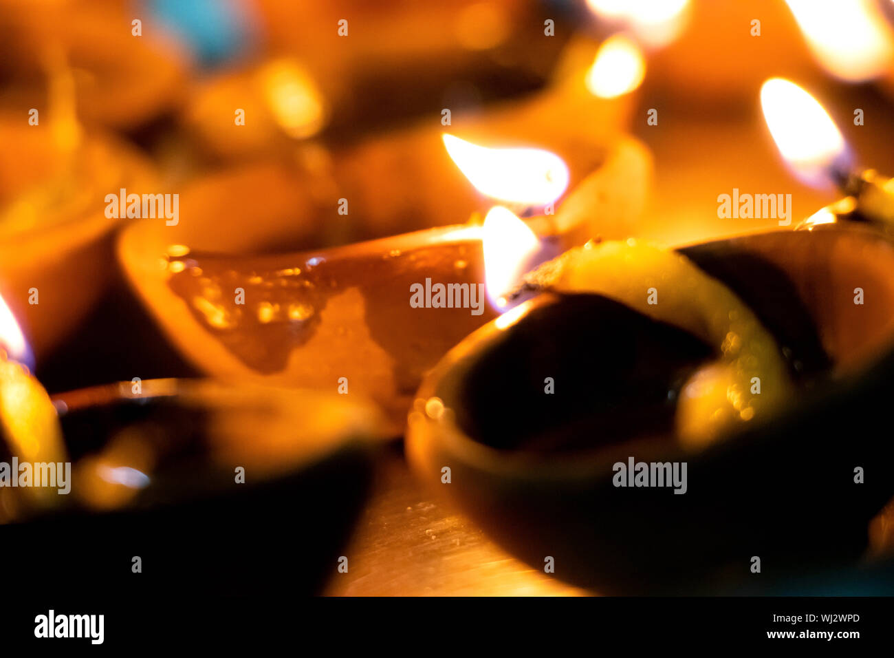 Riprese macro di diyas essendo illuminata da mano o candela per i religiosi indù festa di Diwali. Queste colorate earthern pentole contenere olio e uno stoppino di cotone t Foto Stock