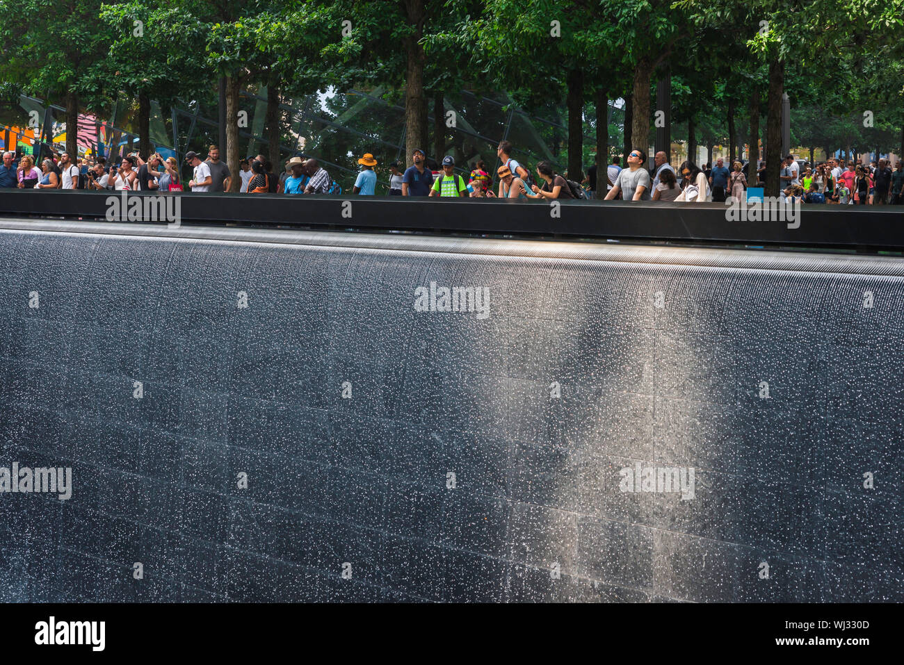 9/11 Memorial, vista della gente che guarda all'enorme fontana della North Tower che riflette la piscina al 9/11 Memorial site a Manhattan, New York City. Foto Stock