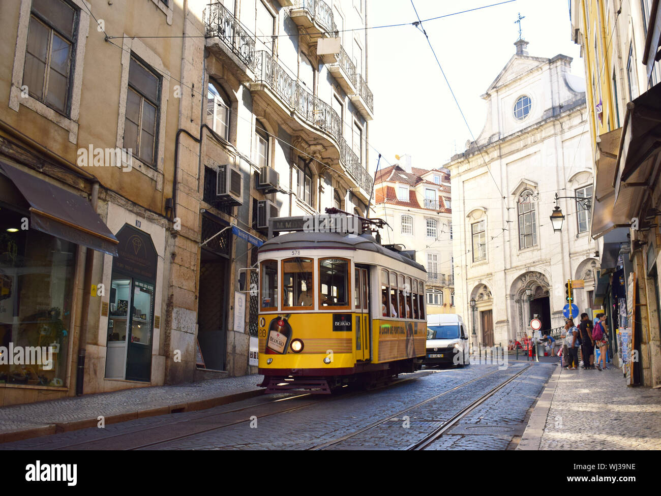 Un tradizionale tram giallo nelle strette vie della città vecchia di Lisbona Portogallo Foto Stock