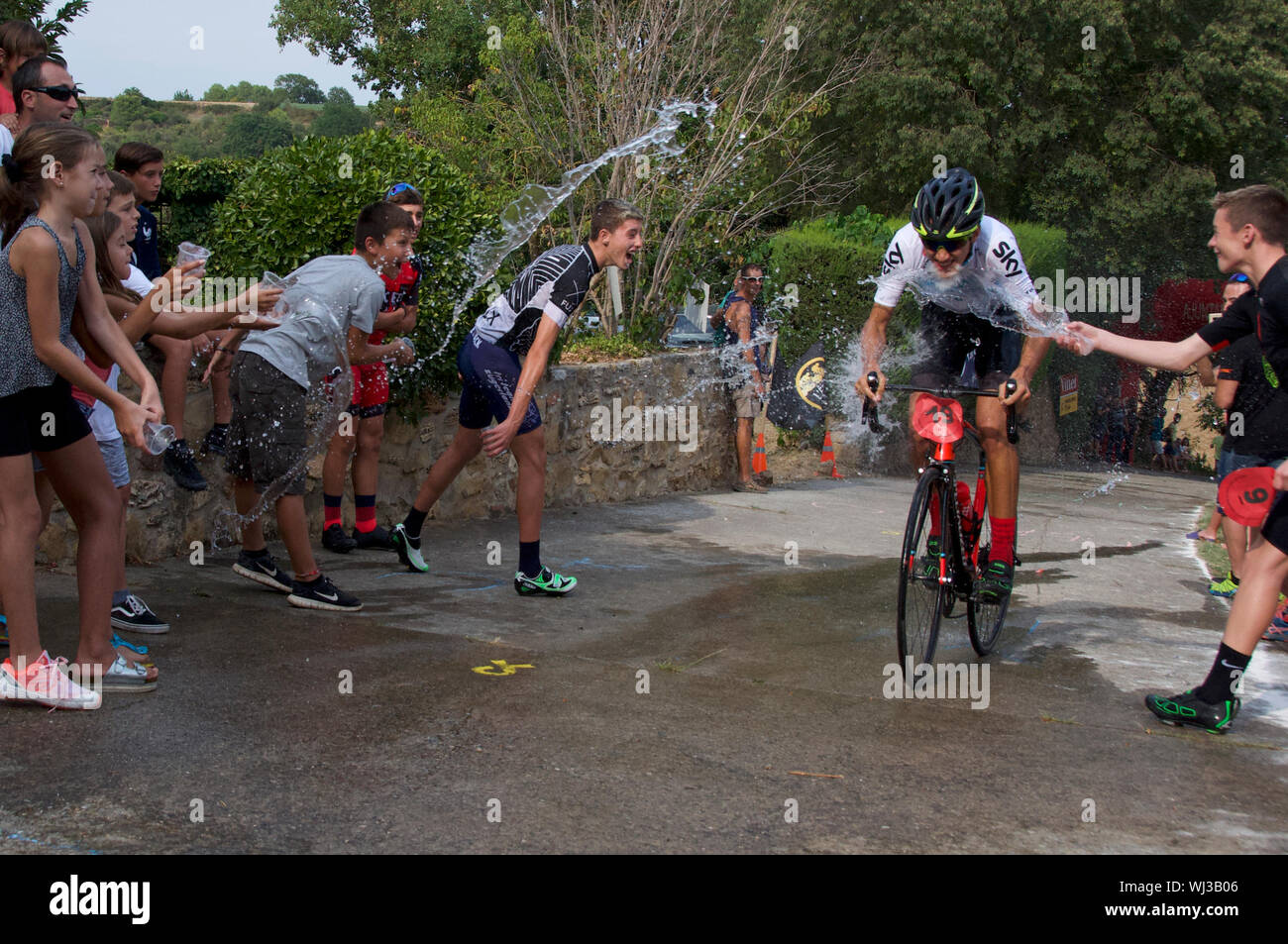 Azione dal ciclo di razza, un breve tratto in salita, nel villaggio di Mianigues, Pla d'lestany, Girona, Spagna. I concorrenti sono cosparsi di fan. Foto Stock