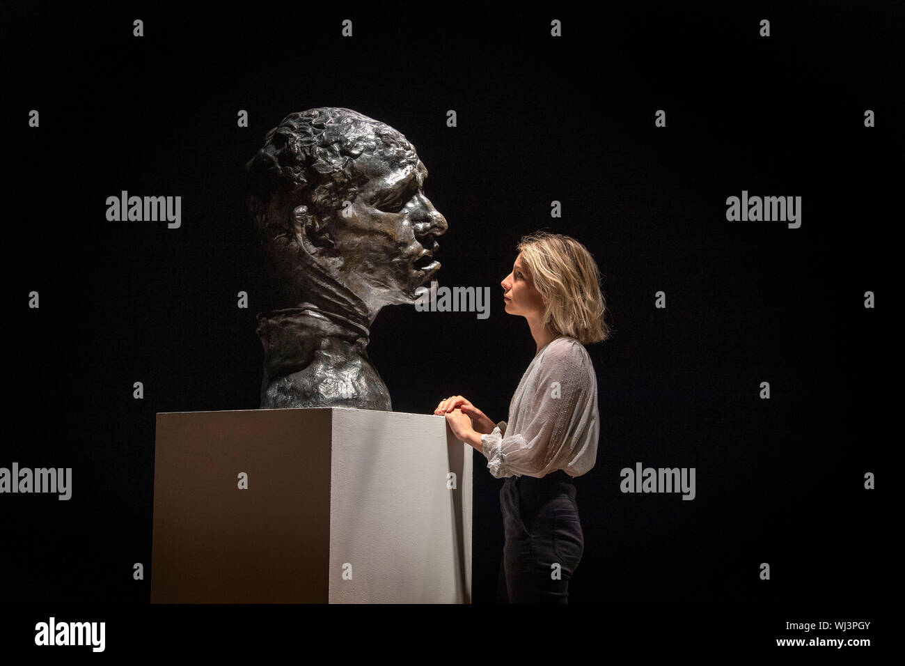 Un membro del personale guarda l'ONU des Bourgeois de Calais: Tete colossale de Pierre de Wissant da Auguste Rodin, che fa parte di una raccolta di sculture di Rodin a Bonhams a Londra centrale prima che essi siano messi in vendita dalla Casa d'aste. Foto Stock