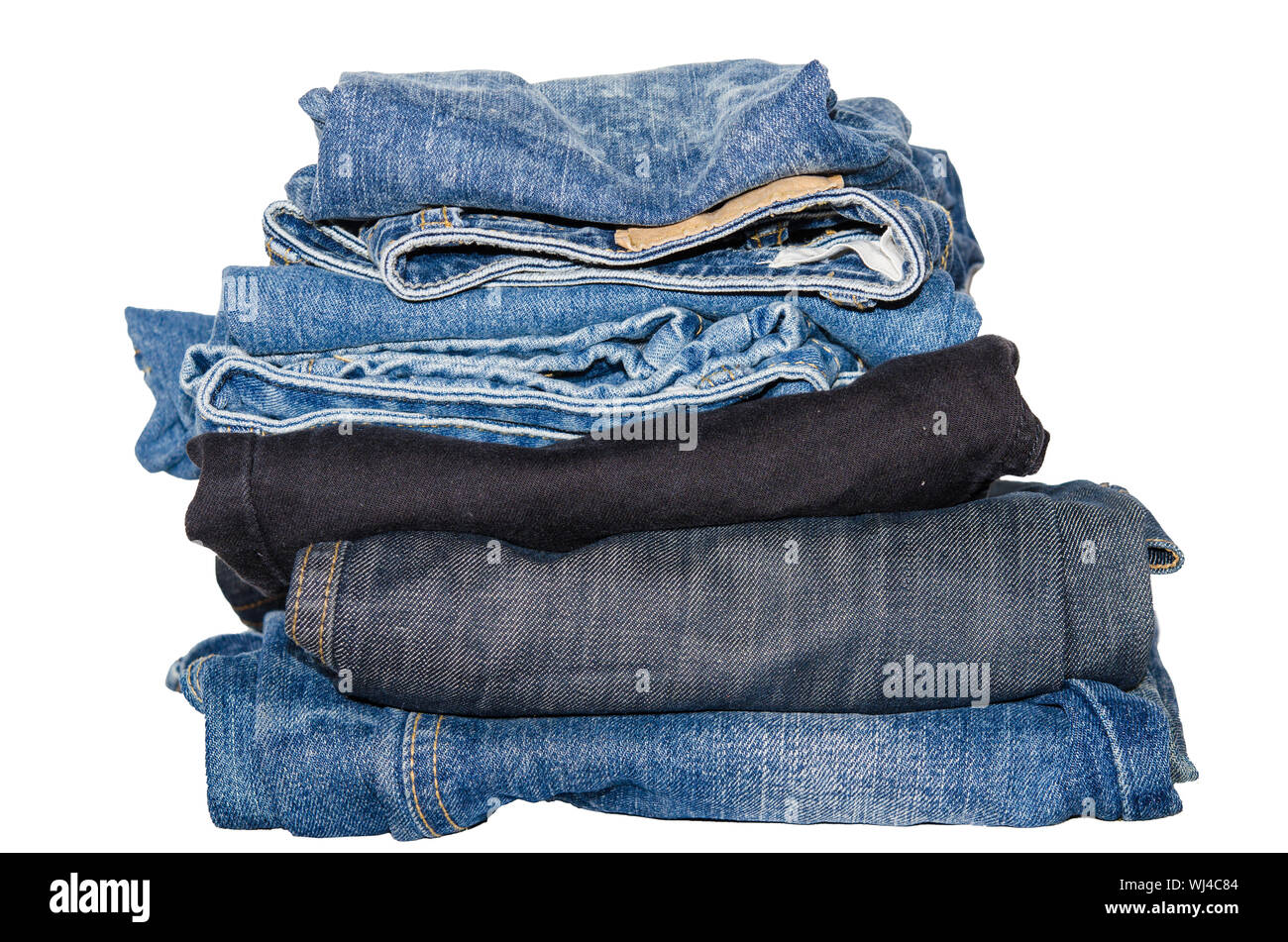 Close-up di jeans impilate contro uno sfondo bianco Foto Stock