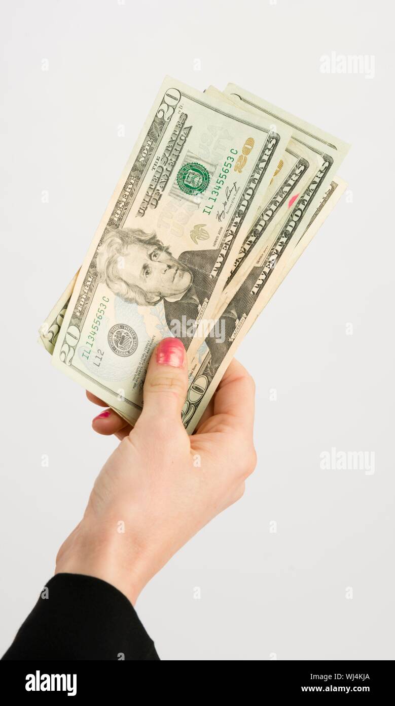 Mano femmina trattiene il pagamento in contanti in valuta dollaro venti denaro spalle verde Foto Stock