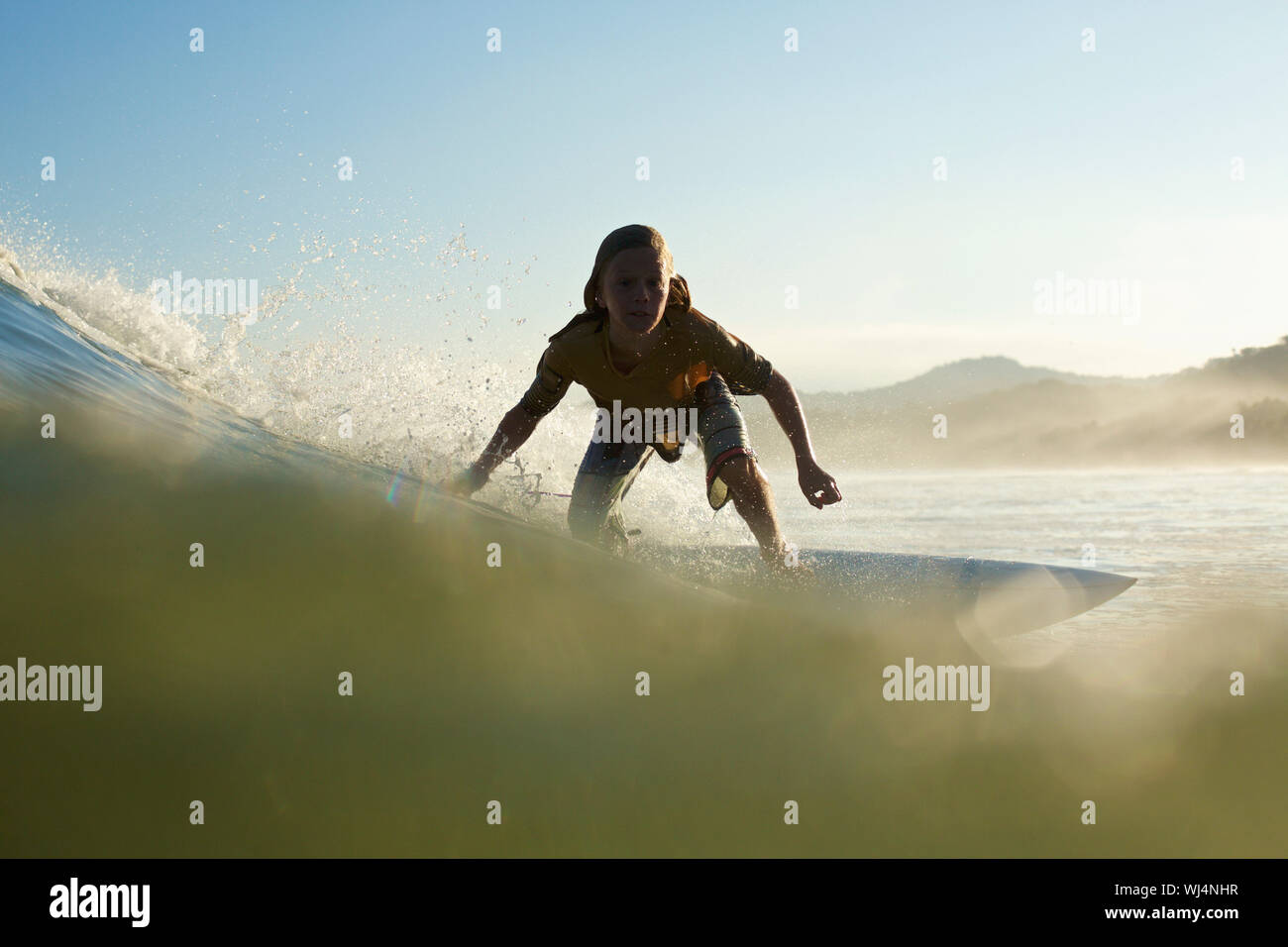 Silhouette boy surfer a cavallo delle onde oceaniche Foto Stock