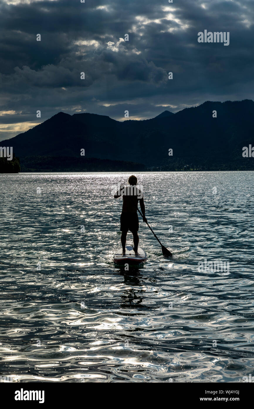 Silhouette uomo paddleboarding sul soleggiato, idilliaco Lago Walchensee, Baviera, Germania Foto Stock