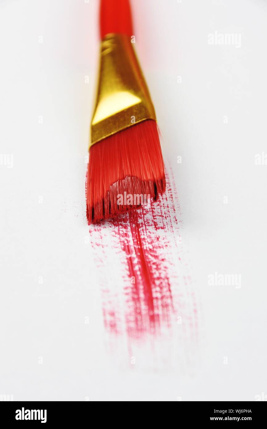 Angolo di Alta Vista del pennello e la vernice rossa su sfondo bianco Foto Stock