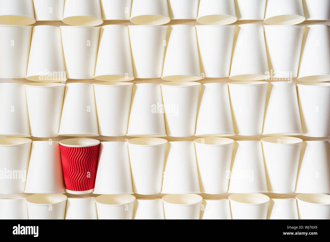 La configurazione di sfondo bianco di caffè bicchieri di carta con red cup in piedi fuori in un angolo. Concettuale con spazio di copia Foto Stock