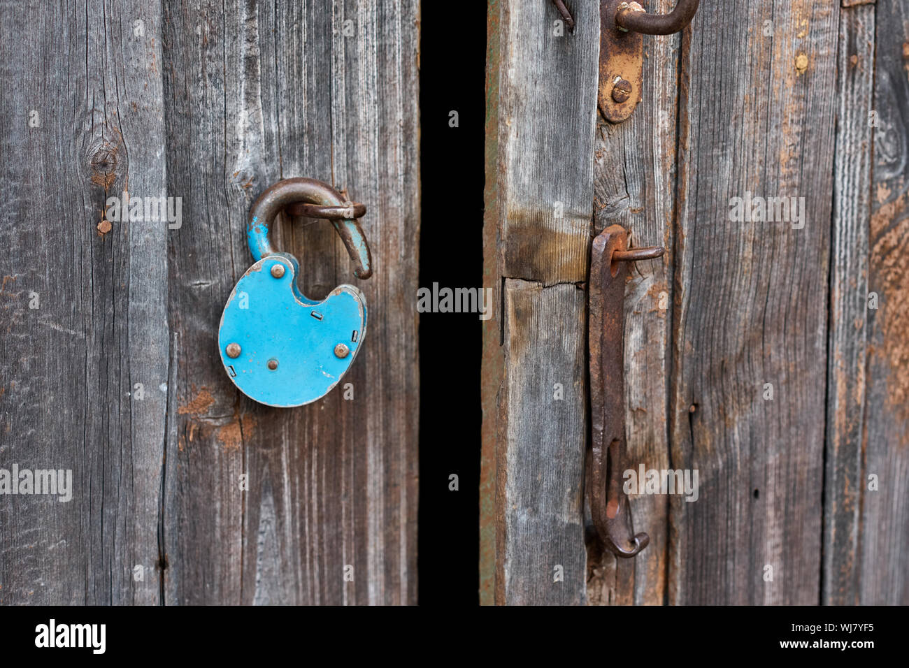 Blue vecchio arrugginito lucchetto aperto sulla porta di legno Foto Stock