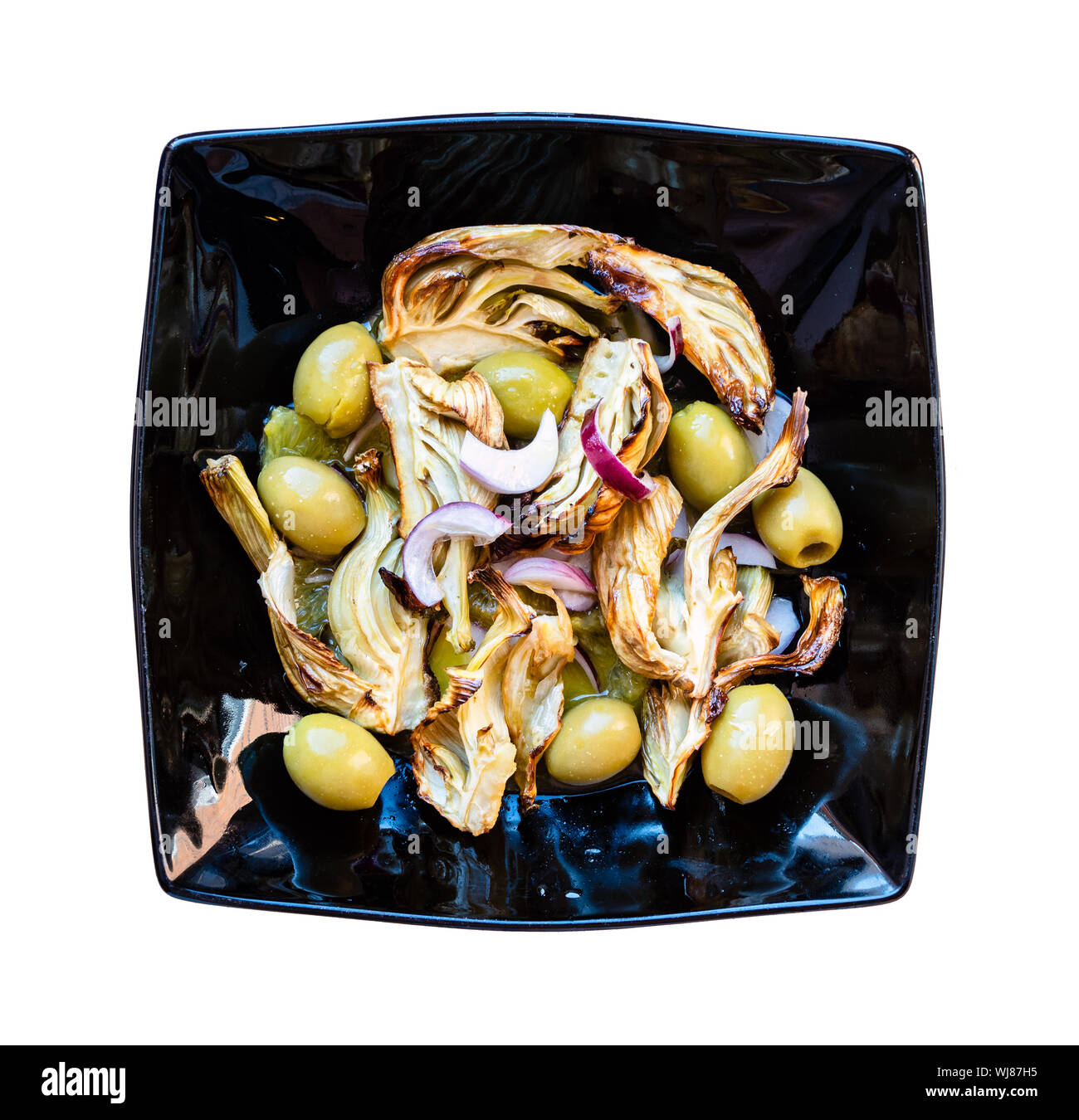 Cucina francese - vista superiore del finocchio cotto levetta con olive e cipolla rossa e dressing di arancia, il succo di limone e olio di oliva sulla piastra nera intaglio sulla w Foto Stock