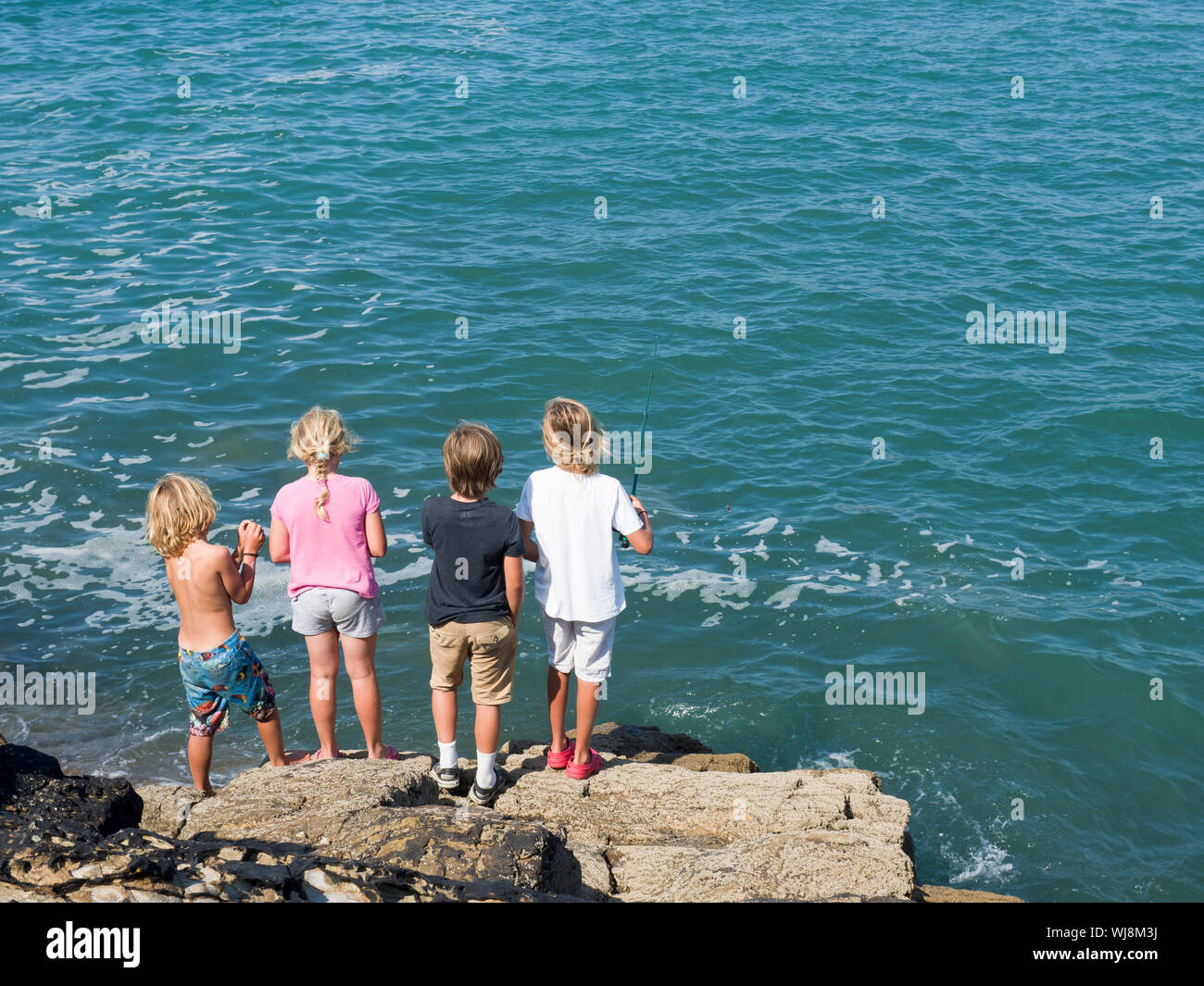 I bambini la pesca dalla scogliera, Bude, Cornwall, Regno Unito Foto Stock