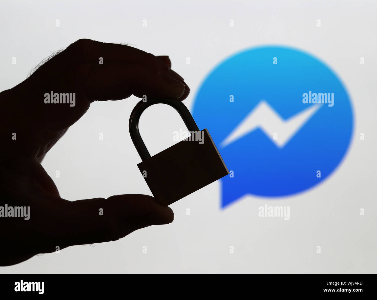 Un uomo con un lucchetto davanti allo schermo di un computer visualizzando il Facebook Messenger logo per illustrare la protezione dei dati (solo uso editoriale) Foto Stock