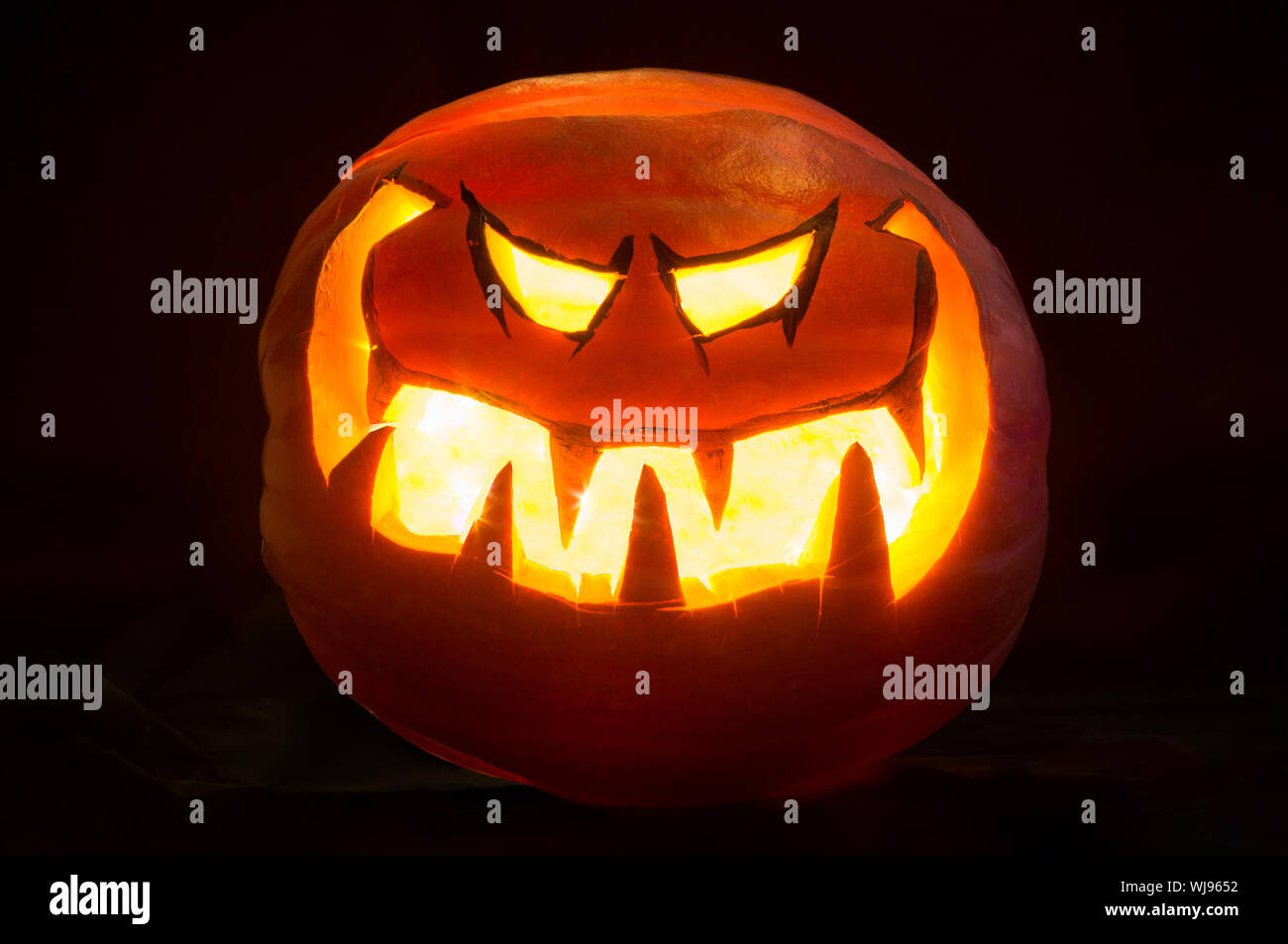 Halloween sorriso di zucca e occhi misero per la festa notte. Sfondo nero Foto Stock