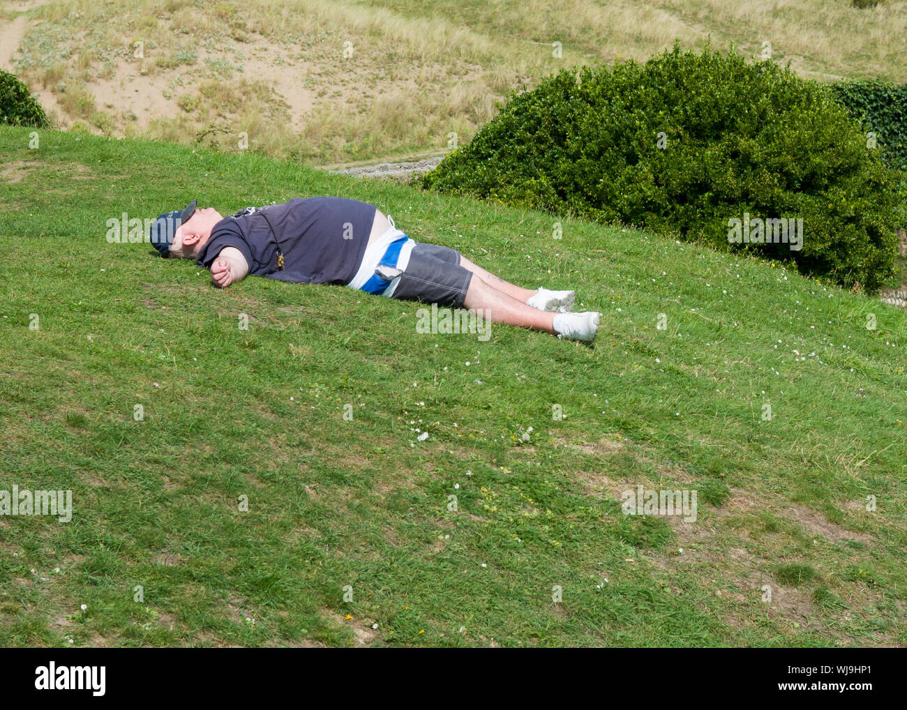 Il sovrappeso uomo addormentato sull'erba, REGNO UNITO Foto Stock