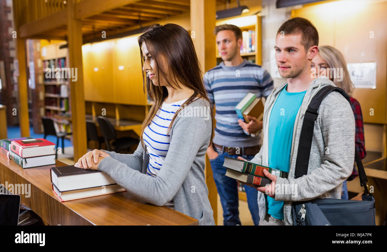 I giovani studenti in una fila allo sportello in college library Foto Stock