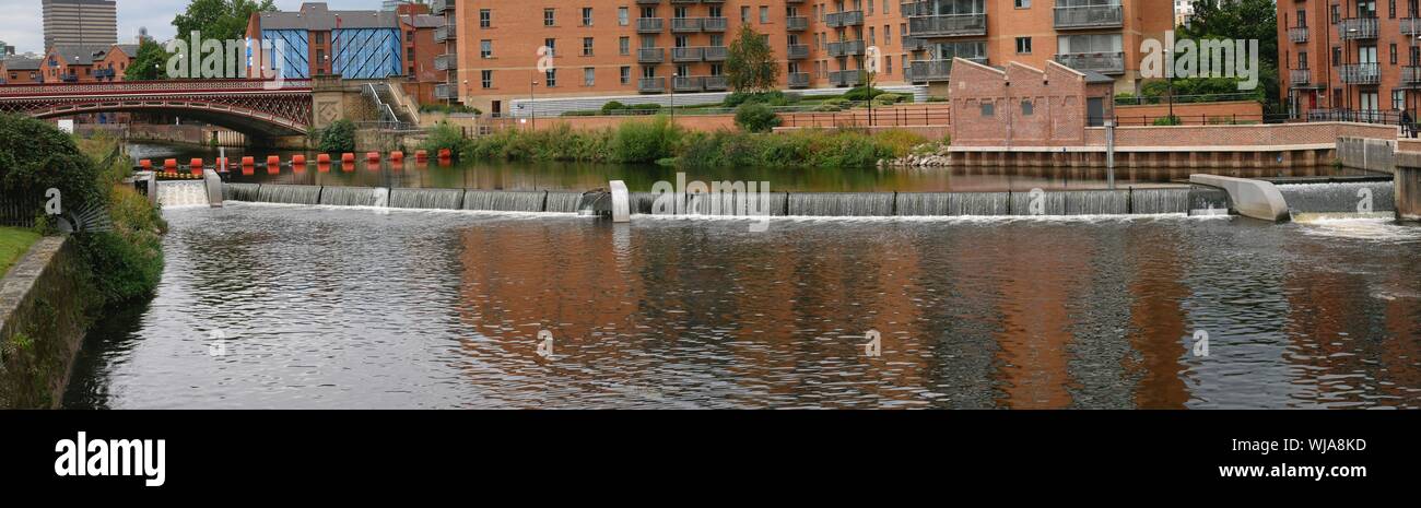 Weir e trabocca di colore arancione del braccio e del ponte sul fiume aire in Leeds Yorkshire Inghilterra Foto Stock