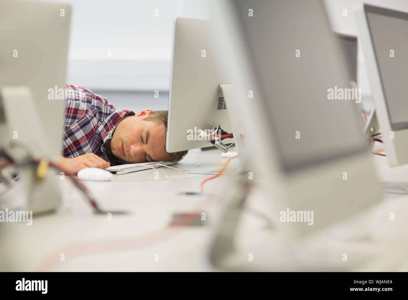 Bello studente napping in sala computer Foto Stock