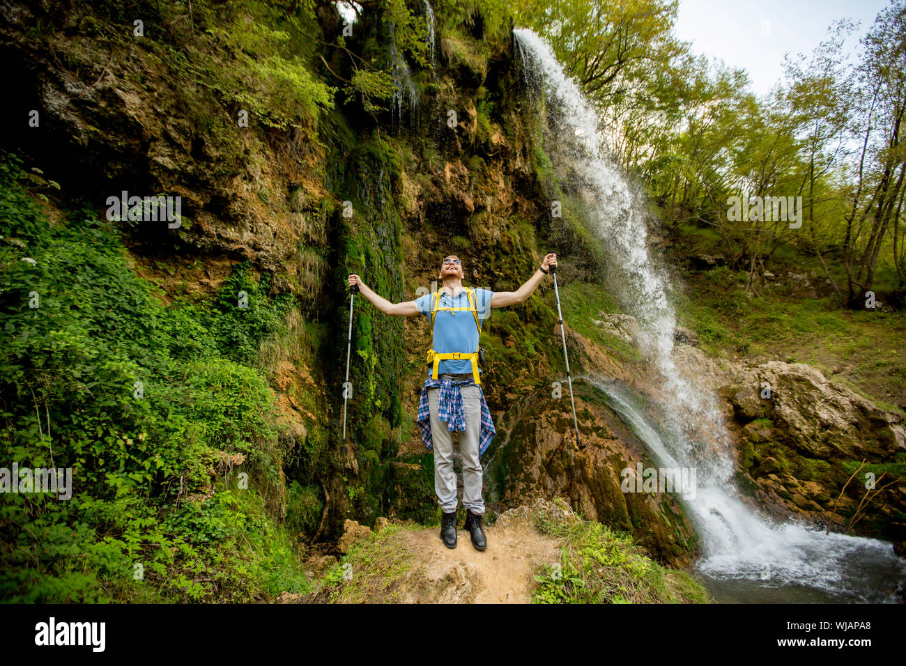 Bel giovane escursionista fermato accanto a una cascata di montagna a riposo Foto Stock