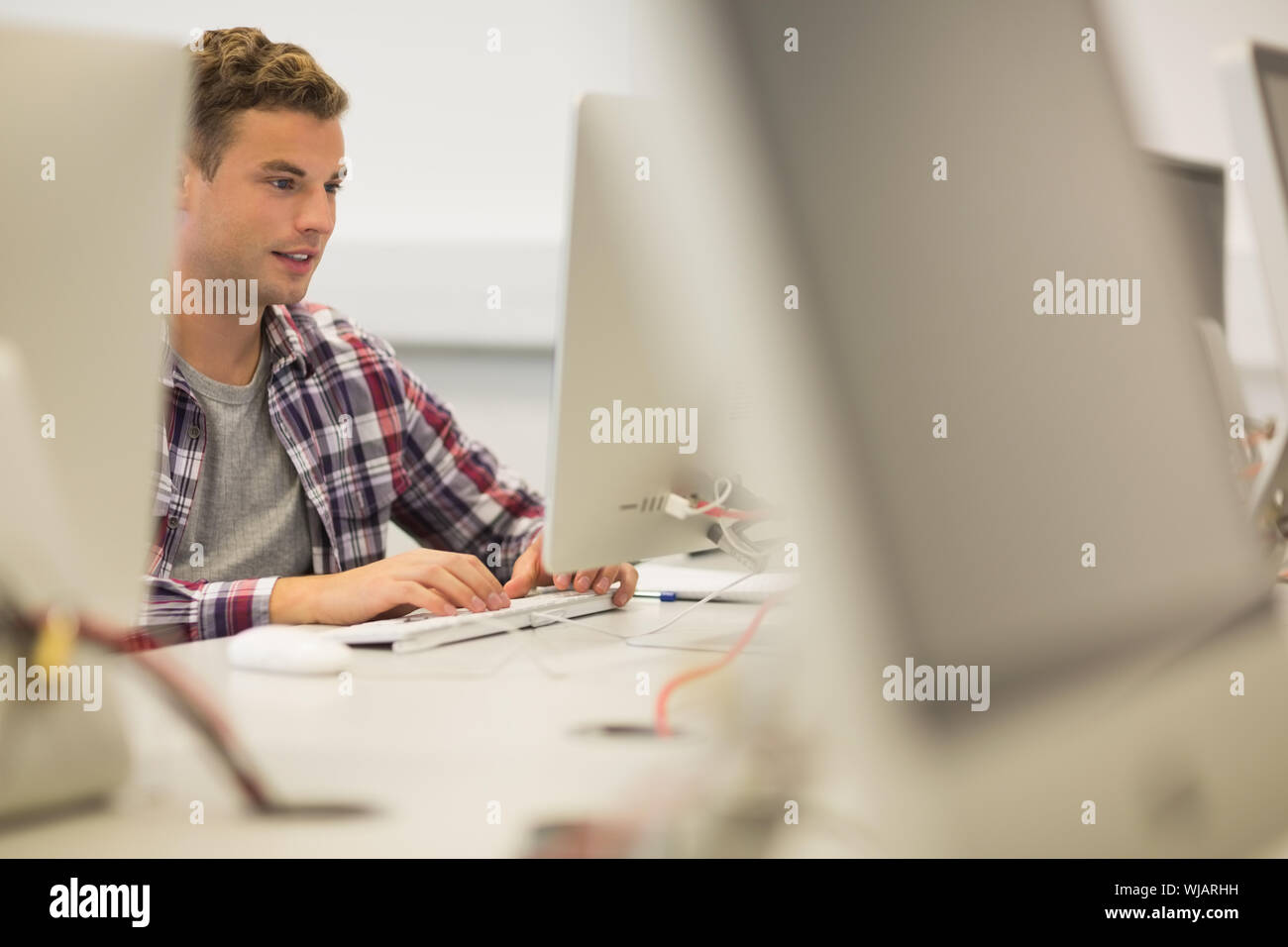 Sorridente bello studente in sala computer Foto Stock