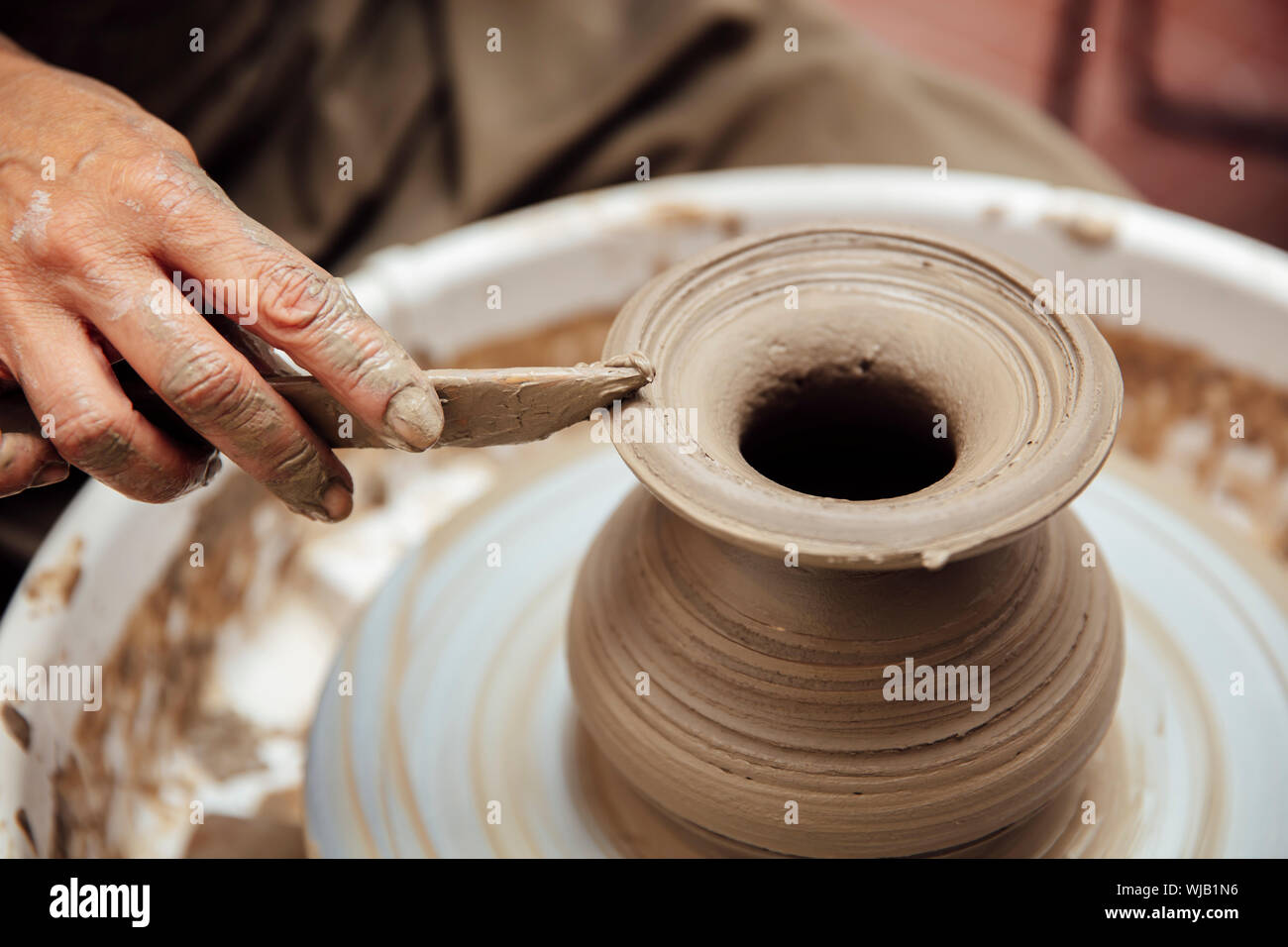 Close up della vista di dettaglio a un senior artista femminile fa di terraglie di argilla su una rotella manuale Foto Stock