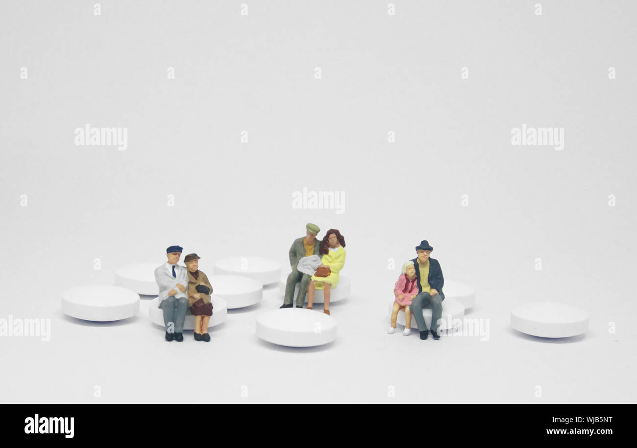 Coppia di anziani famiglia figura seduta su una pila di pillole di bianco. Foto Stock
