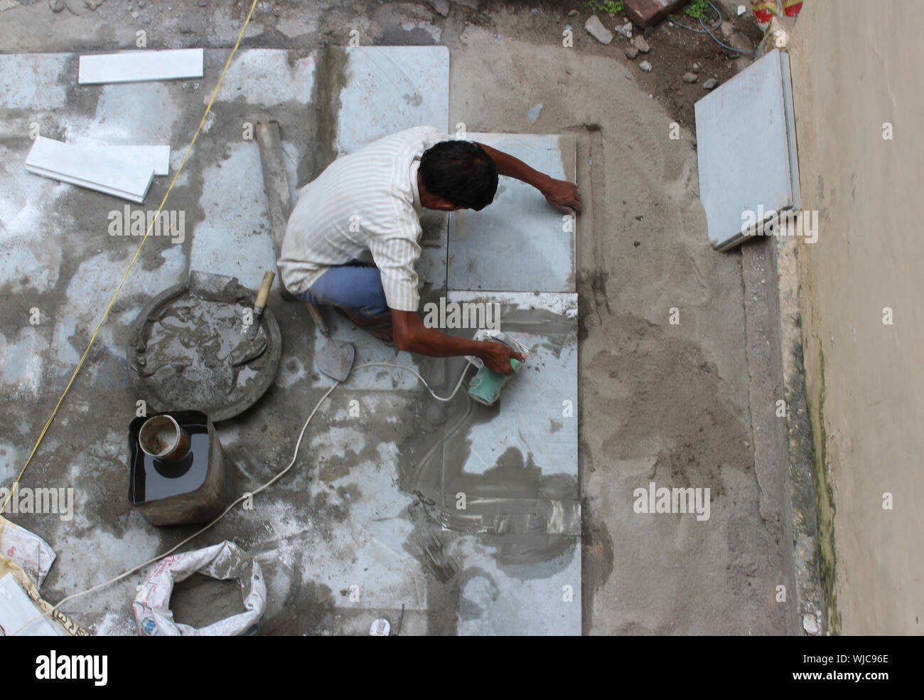 Mason che regge una macchina per il taglio di una lastra di pietra in New Delhi, India Foto Stock