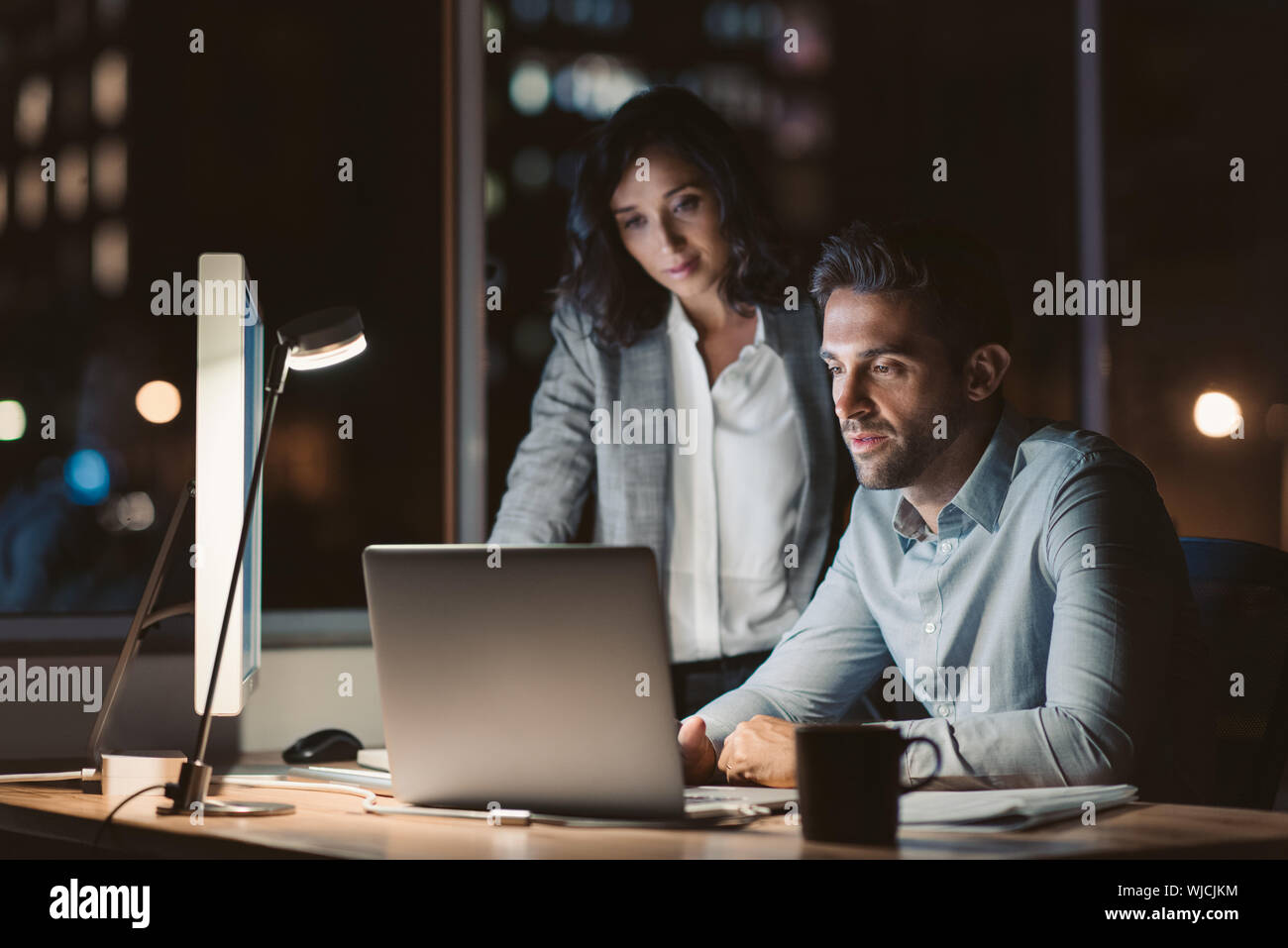 Gli imprenditori che lavorano insieme su un laptop nella tarda serata Foto Stock