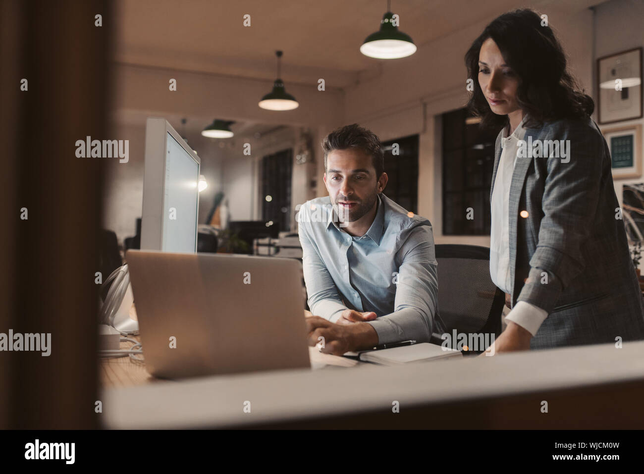 Due giovani colleghi lavora fino a tardi in un ufficio insieme Foto Stock